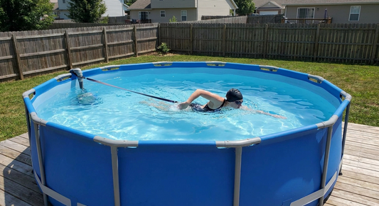 a swimmer swimming in place against a current in a metal-frame above-ground backyard pool