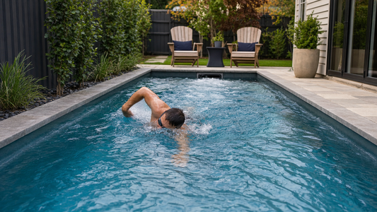 A swimmer training in place against a swim jet current in a small backyard pool