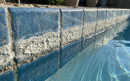 White calcium scale forming along a pool waterline