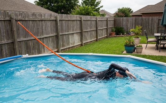 A swimmer doing freestyle in place in a small backyard pool